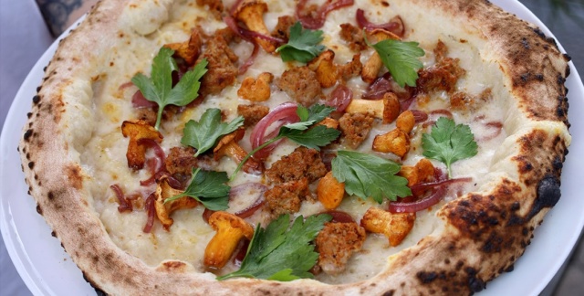 Pizza "Beppe" mit Parmesan-Crème, Parmigiano DOP, Provolone, Kräuterseitlinge, Bliesgau Iberico Salsiccia, karamellisierte Zwiebeln und Blattpetersilie