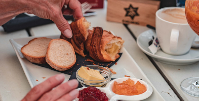 Frühstück mit Café, Croissants, Brötchen, Butter, Marmelade, Sandwichs und Getränken