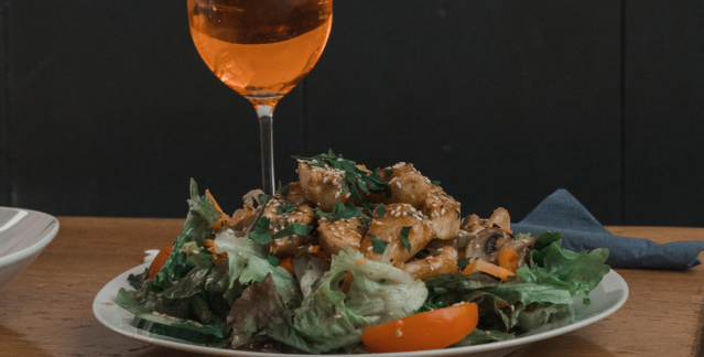 Ein Glas Aperitif und ein Hühnchen Salat